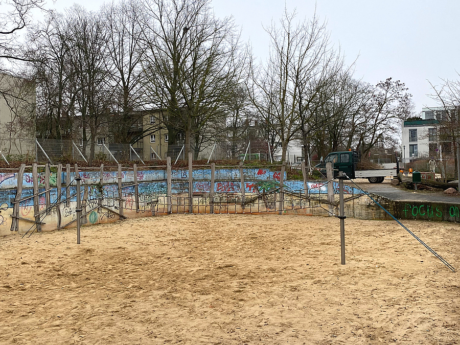 Sandspielfeld mit Netz und Mauer mit Graffiti im Winter