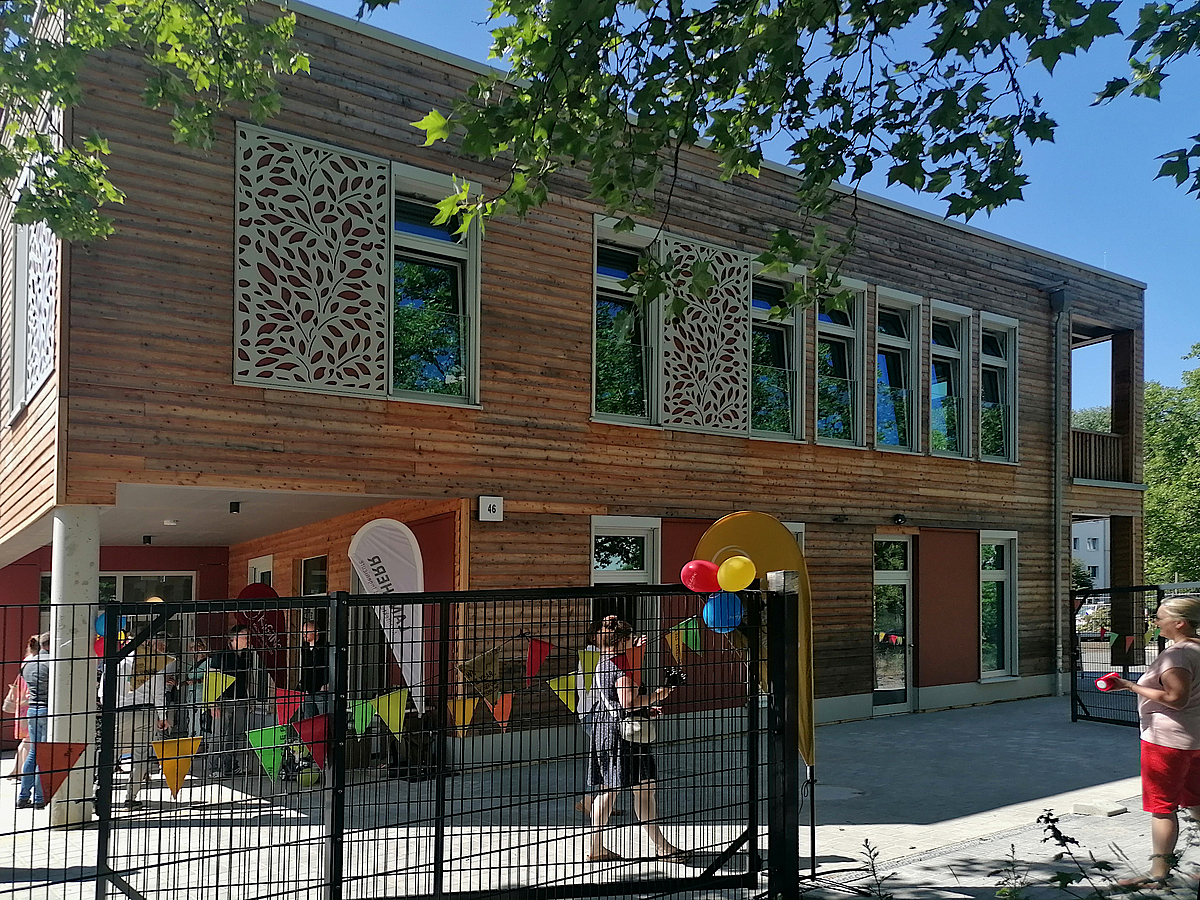 Geschmückter Eingang zweigeschossiger Holzbau mit Ornamenten, Menschen