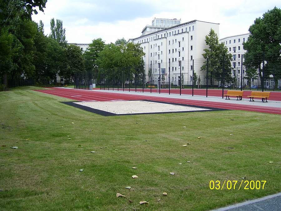Weitsprung- und Sprintbahn, Ballspielplatz auf Kunststoff, Grün, große Wohngebäude aus den 1950er Jahren