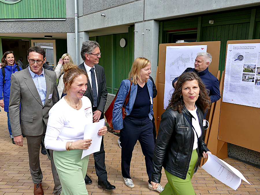 Gruppe geht an kleiner Ausstellung im Freien vorbei