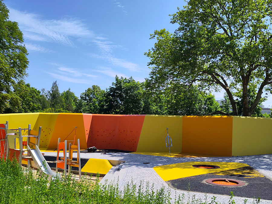 Spielfläche mit Mauer zum Bouldern in Gelb, Orange und Rot