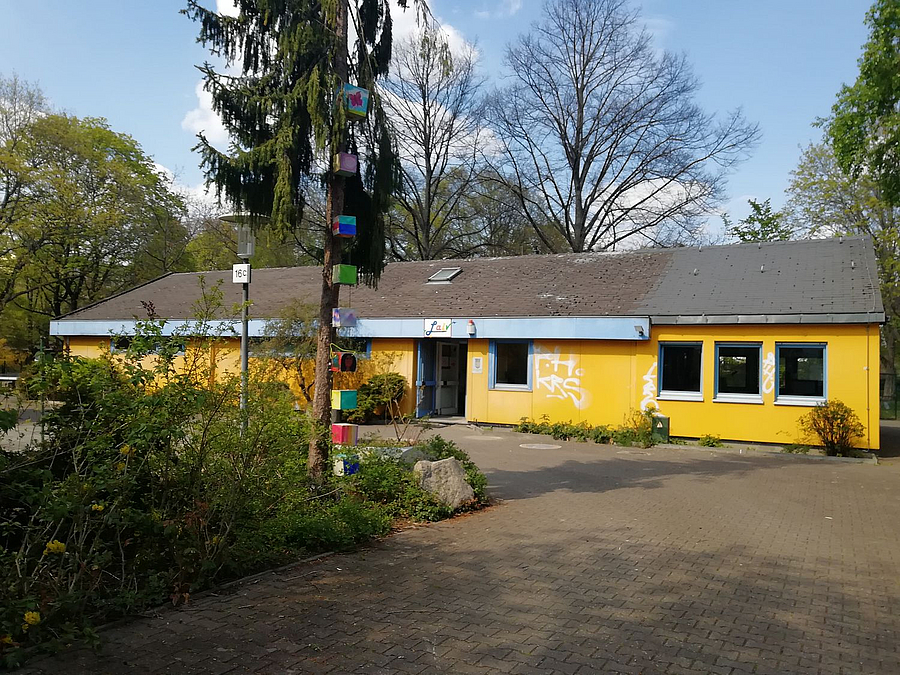Gelber Flachbau mit Pflaster und Grünfläche