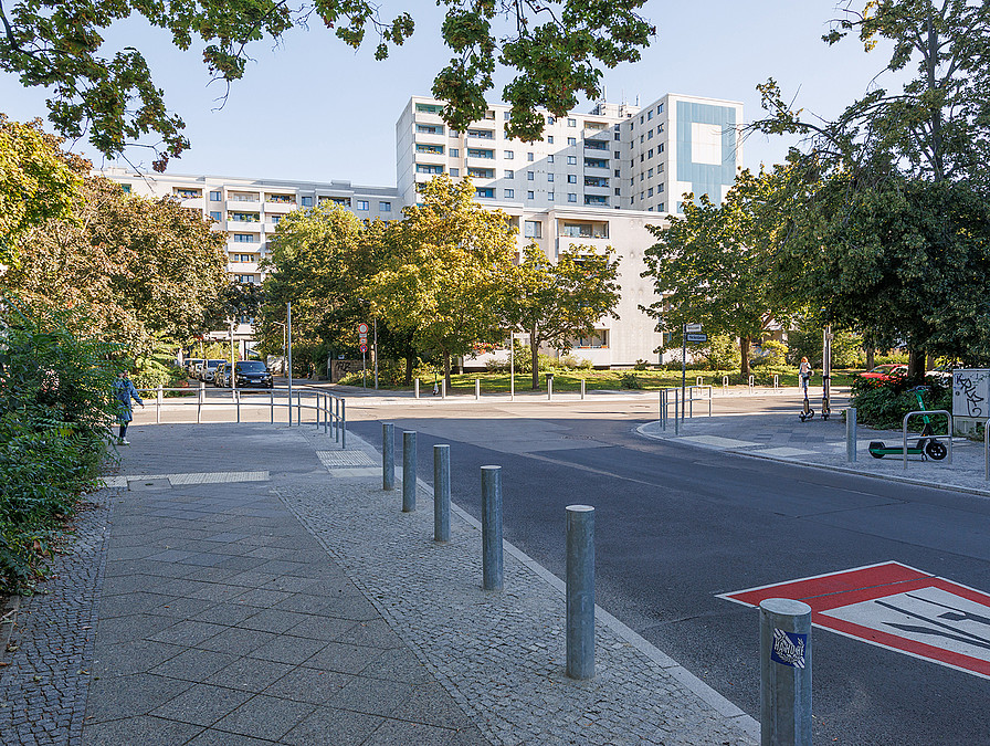 Kreuzung vor Hochhäusern. Auf der Straße Verkehrszeichen "Achtung Fußgänger" aufgesprüht