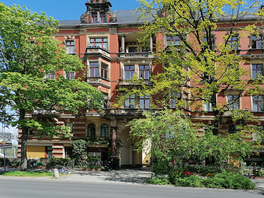 Backsteingebäude hinter Bäumen und Blumen