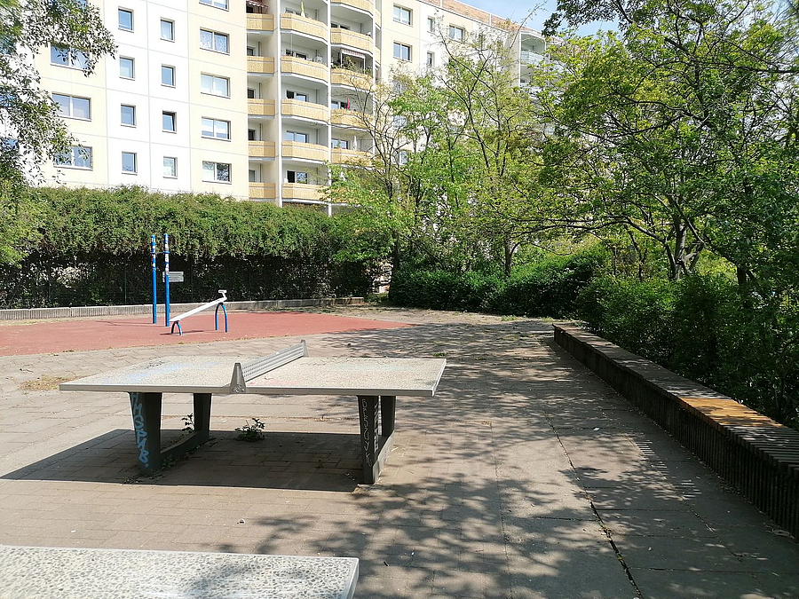 Tischtennisplatte, Kraftgerät, im Hintergrund Plattenbau