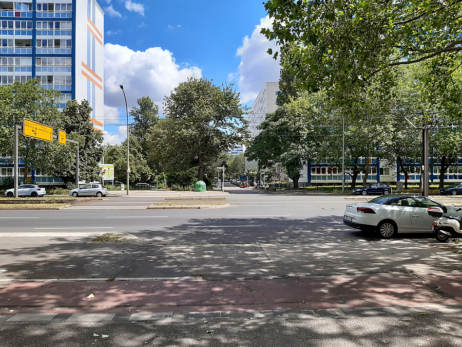 Blick über breite Straße, Bäume, Plattenbauten auf der anderen Seite