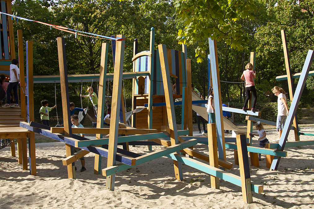 niedrige Holzbalken und Pfosten in blau-grün mti wenigen Kindern