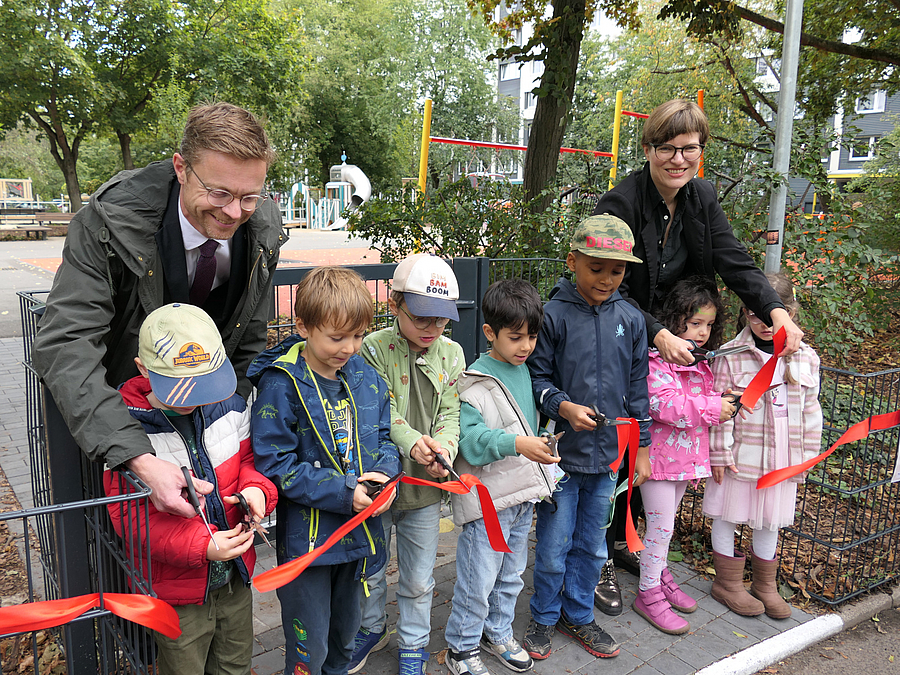 Kinder und zwei erwachsenen zerschneiden rotes Band