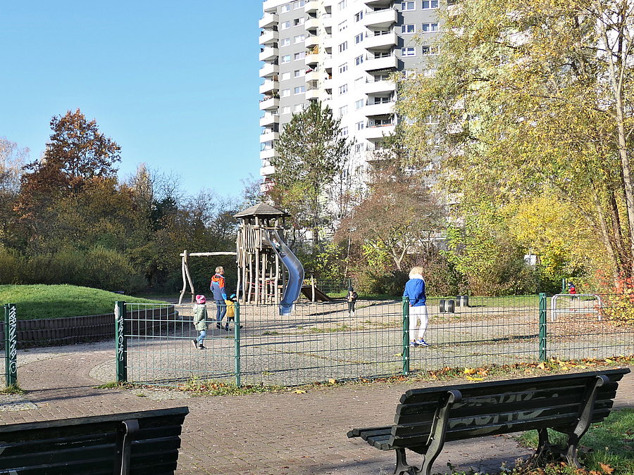 Der Spielplatz im Herbst 2022  Wenige Menschen auf Spielplatz vor Hochhaus