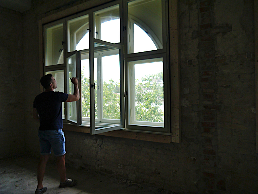 Vielfach gegliedertes Fenster vor halbrunder Fensteröffnung