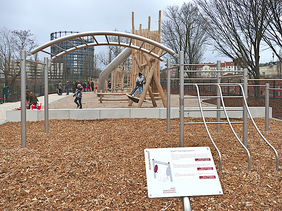 Schild mit Anleitung für Rollstuhltrainer, Calisthenicsanlage auf Holzhäckselfläche auf Spielplatz