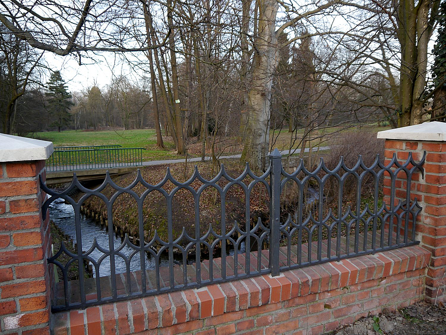 Die Panke schlängelt sich durch den Park und macht seinen besonderen Reiz aus Kunstschmiedegitter in der Einfriedung, Bach und Betonsteg