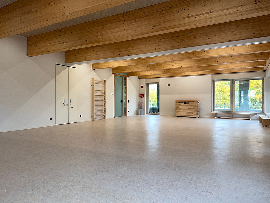 Großer Sportraum mit aus der Decke ragenden Holzbalken