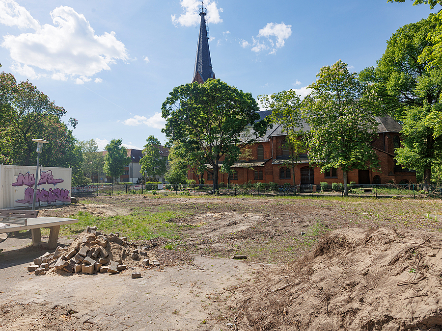 Die Fläche für das Jugend- und Stadtteilzentrum ist bereit Planierte Fläche, im Hintergrund Kirche