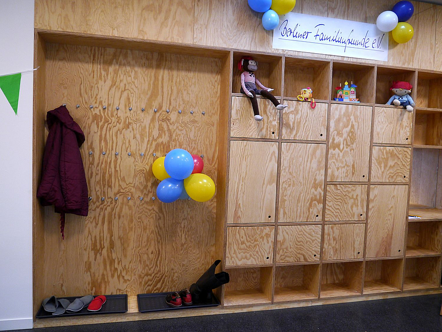 Sperrholzfächer und offene Garderobe mit Mantel und Luftballons