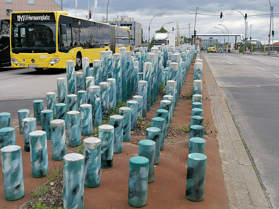 Wellen aus blau gefärbten Pollern auf Mittelinsel, BVG-Bus