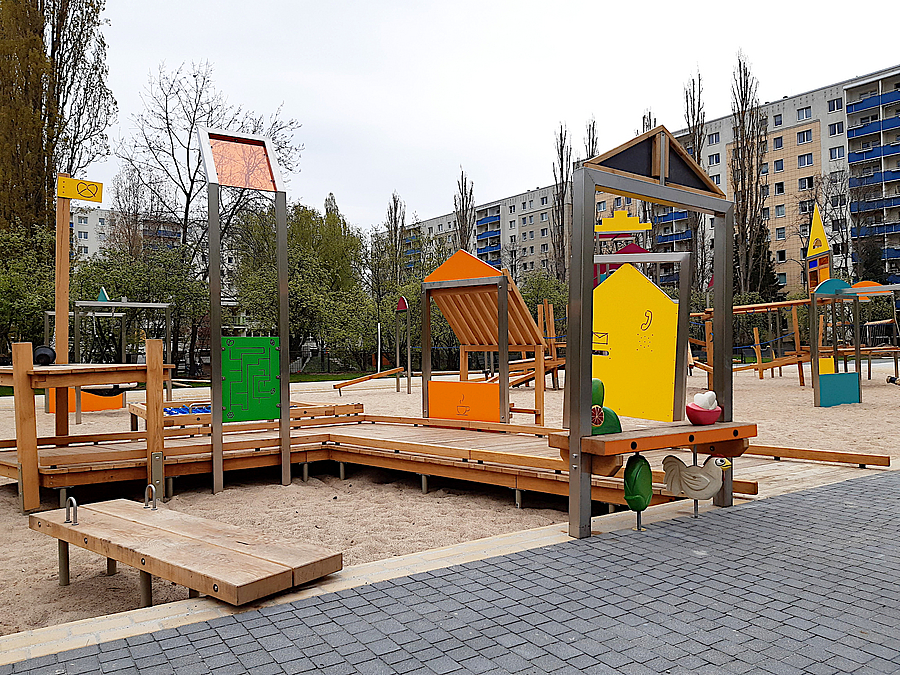 Das "Dorf der Zukunft" ist fast fertig Holzsteg über Sandspielfläche, farbige Rahmen und Dächer