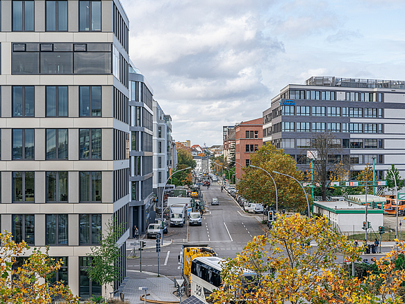 Straße mit Geschäftsbauten und vielen parkenden Autos
