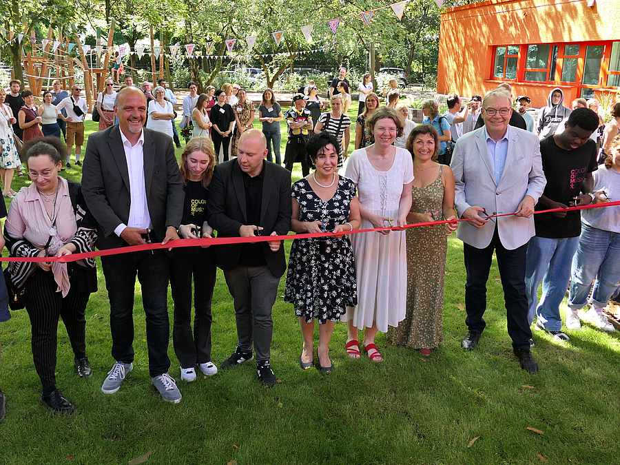 9 und mehr Personen am roten Band im Garten mit Scheren