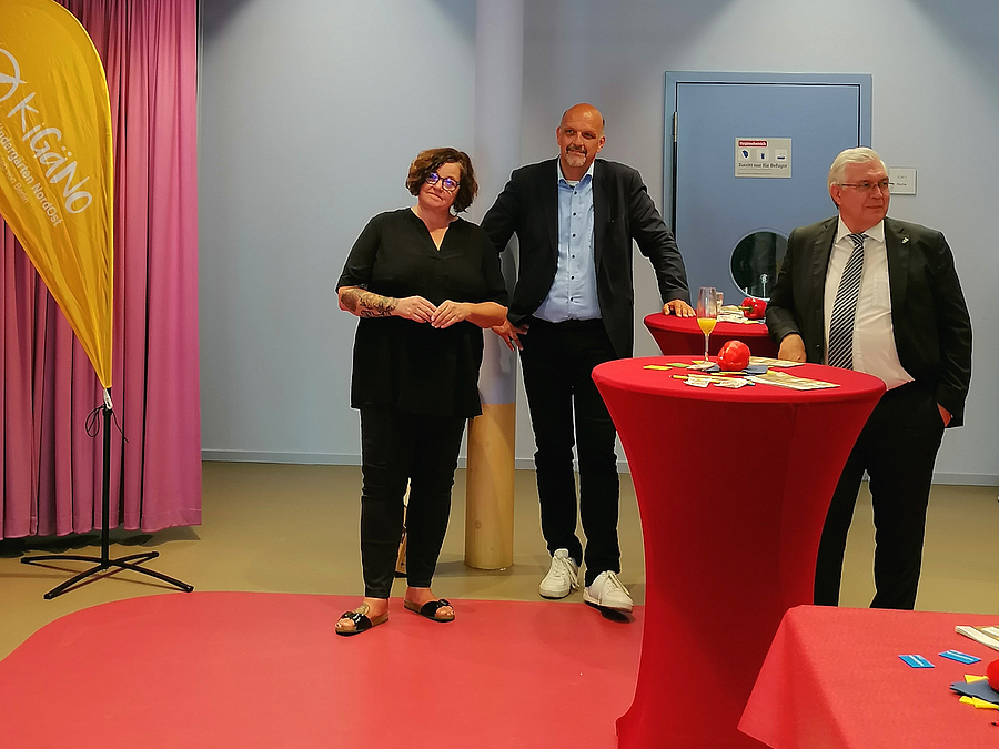3 Personen an rotem Stehtisch
