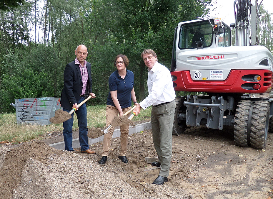 Symbolischer Spatenstich am 24.7.2014 3 Personen mit Spaten, dahinter Bagger