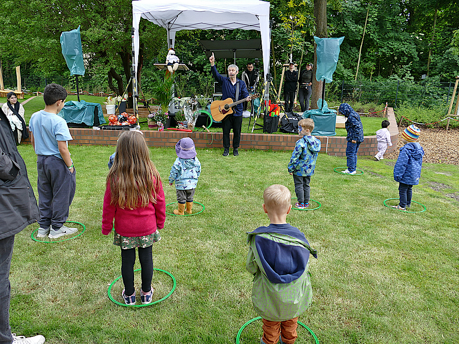 Kinder im Spiel auf der Wiese mit Musiker