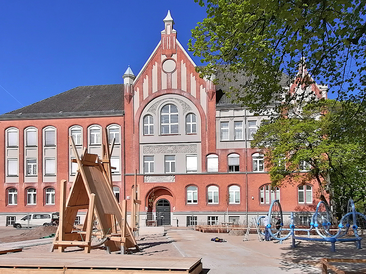 Baustelle mit altem Schulgebäude und großer Holzhütte im Bau