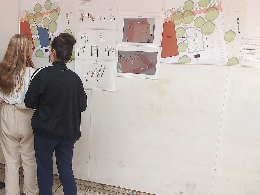 Am 13. Oktober wurden im Geschwister-Scholl-Haus zwei Planungsvarianten vorgestellt 2 Mädchen stehen an Pinnwand mit Plänen