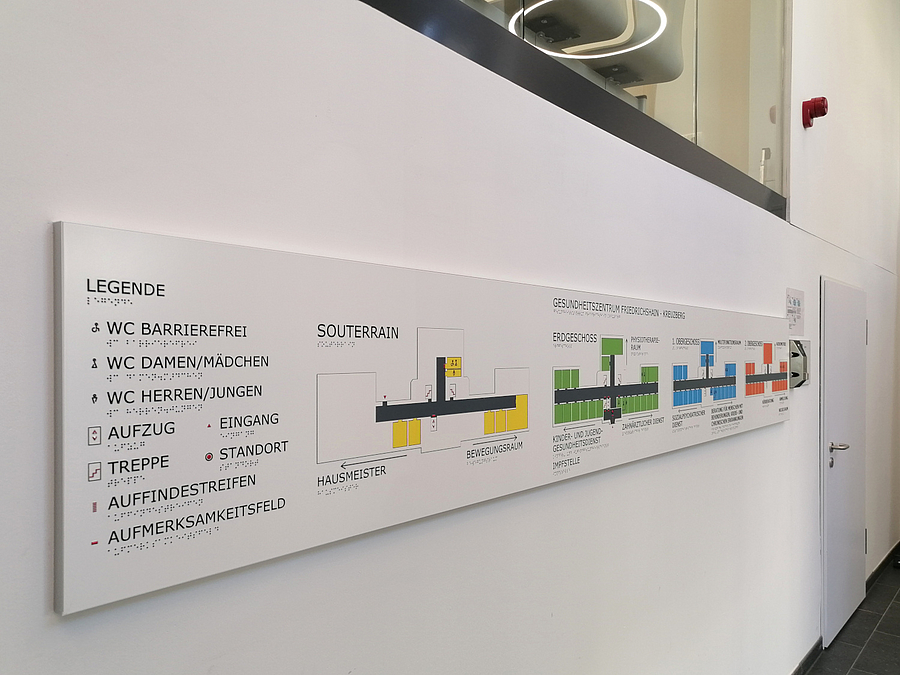 Am Eingang wird der Aufbau des Gesundheitszentrums leicht erfassbar dargestellt Tafel mit farbigem Leitsystem inklusive Brailleschrift