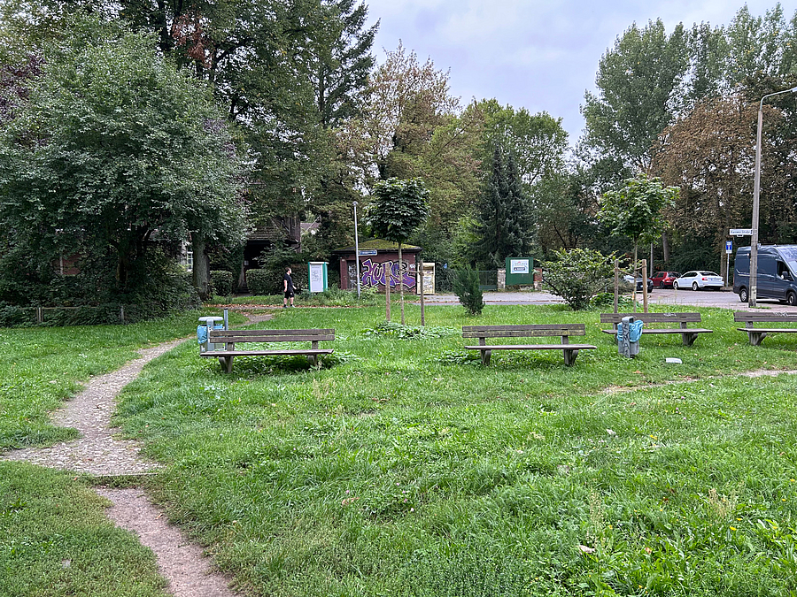 Trampelfad und marode Sitzbänke auf Grünfläche