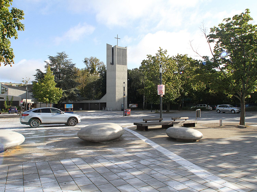 Platz mit Findlingen, Autos, moderner Kirchturm