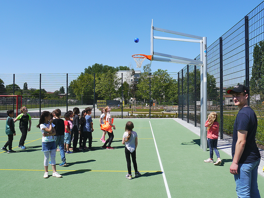 Mädchengruppe am Basketballkorb auf Sportplatz