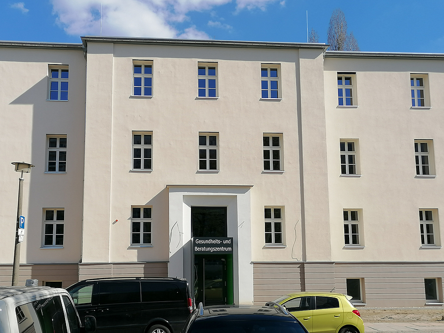 Helle Fassade eines dreistöckigen Gebäudes mit vorspringendem Eingang