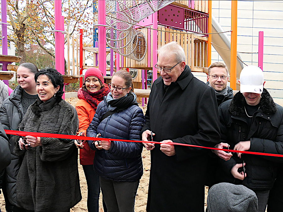 Bezirksbürgermeisterin Emine Demirbüken-Wegner (2. v. links), Berit Binder (SGA), Bezirksstadträtin Julia Schrod-Thiel, Bezirksstadtrat Harald Muschner und Christian Petermann von SenStadt (hinten rechts) Personen durchschneiden ein rotes Band vor Kinderspielgerät