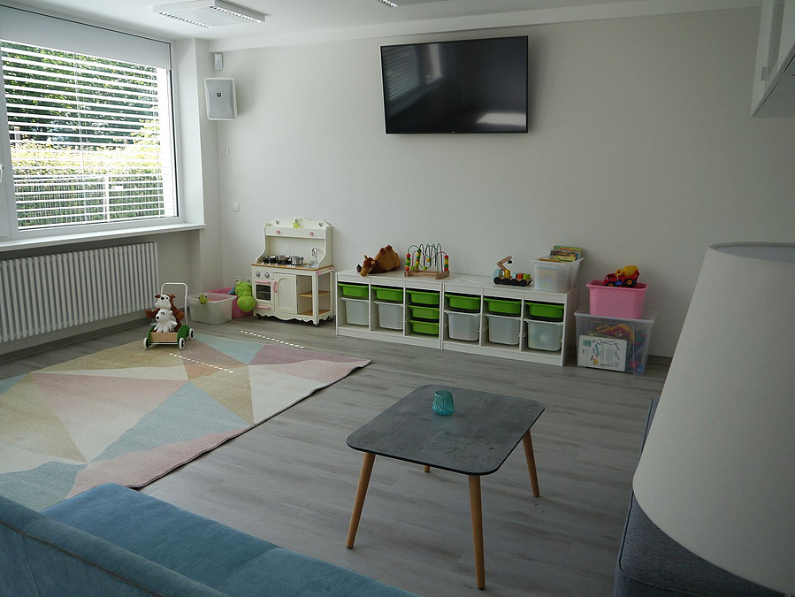 Hell eingerichtetes Zimmer mit Bildschirm an der Wand