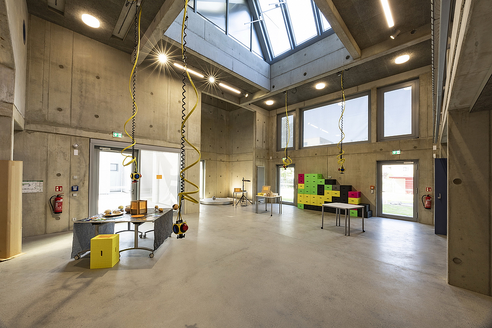 Großer Saal mit großem Oberlicht, mobilen Tischen und Elektroanschlüssen, die von der Decke hängen