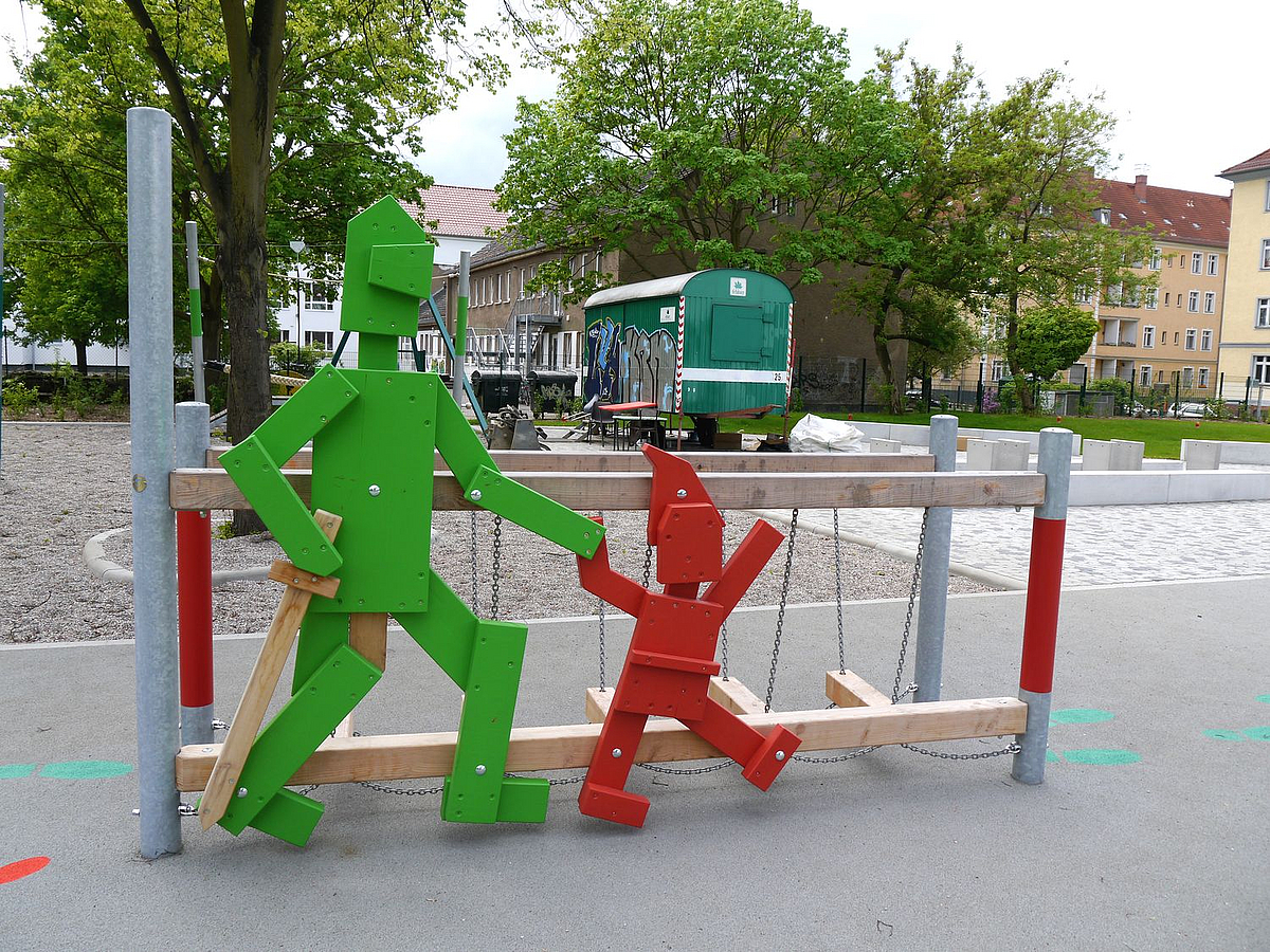 Große grüne Ritter- und rote Zwergenfigur an Balanciergerät