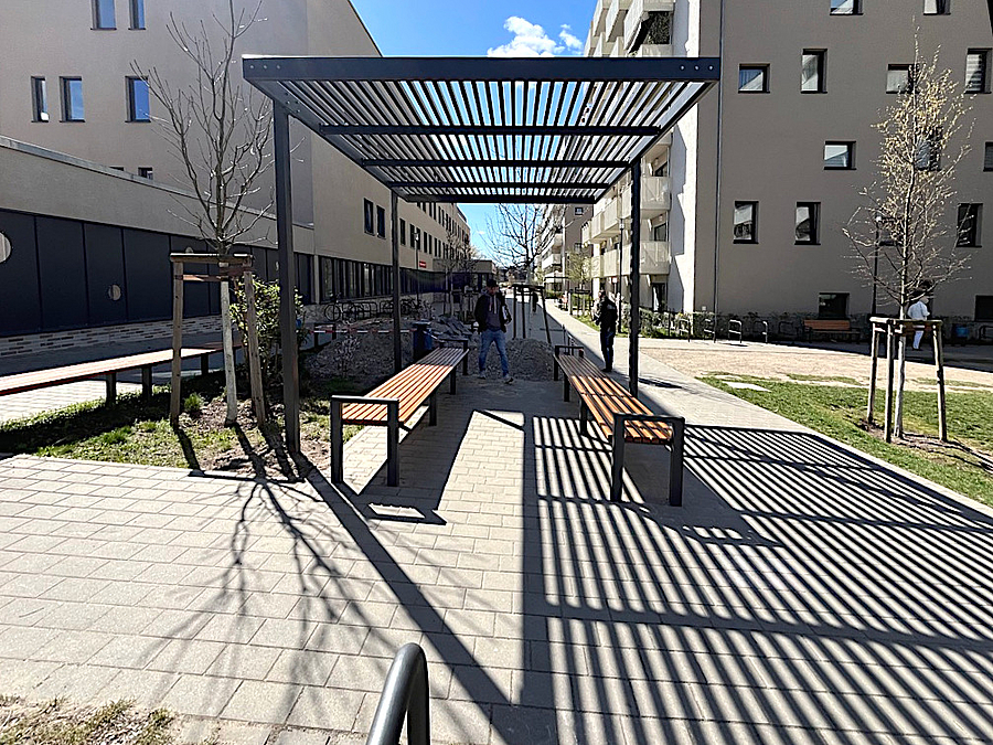 Pergola aus Stahl zwischen Neubauten, jungen Bäume