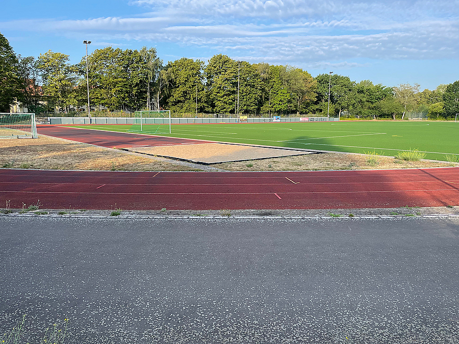 Stadion mit Rasen, Sprunggrube, Tartanbahn, Asphaltfläche