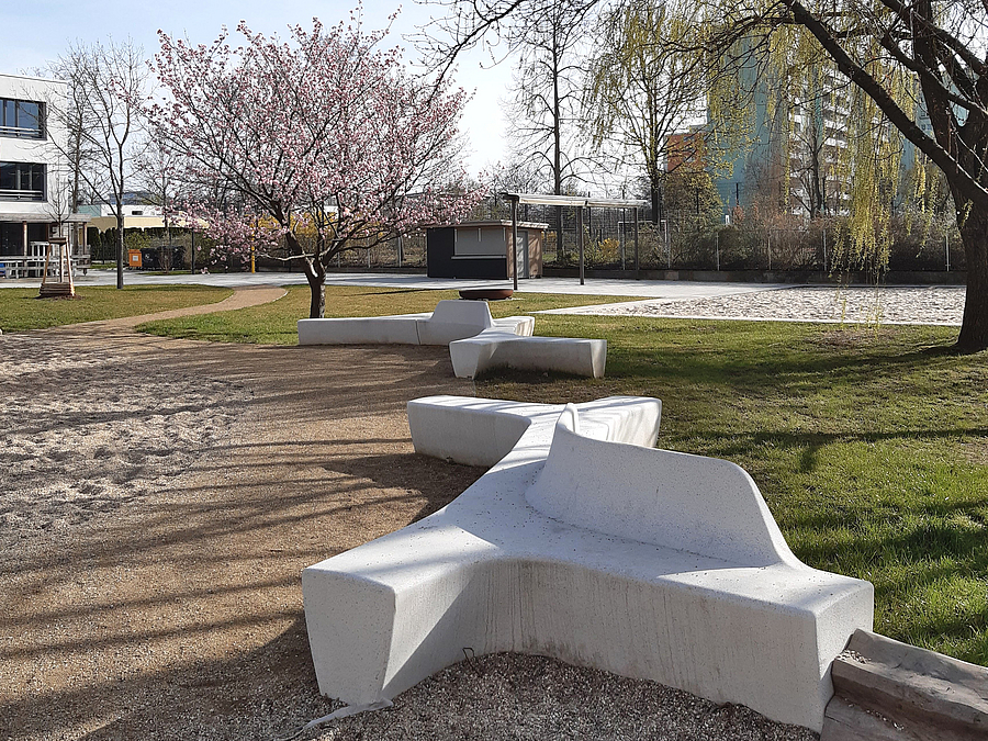 Organisch geformte Betonsitzelemente im frühlingshaften Park