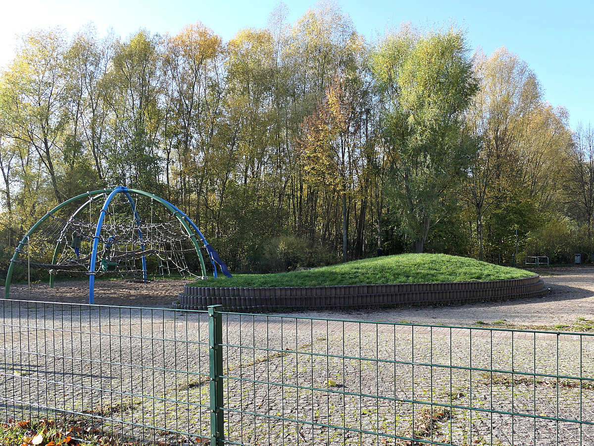 Leerer Spielplatz mit Kletternetz und Rasenhügel ohne Geräte