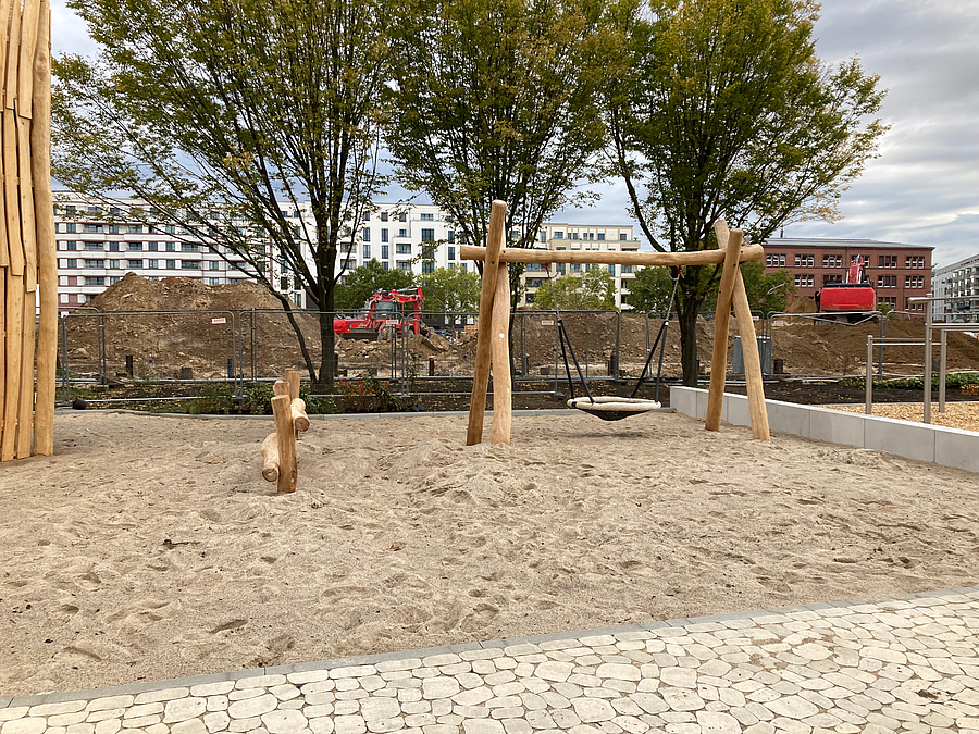 Nestschaukel vor Bäumen und Baustelle im Hintergrund