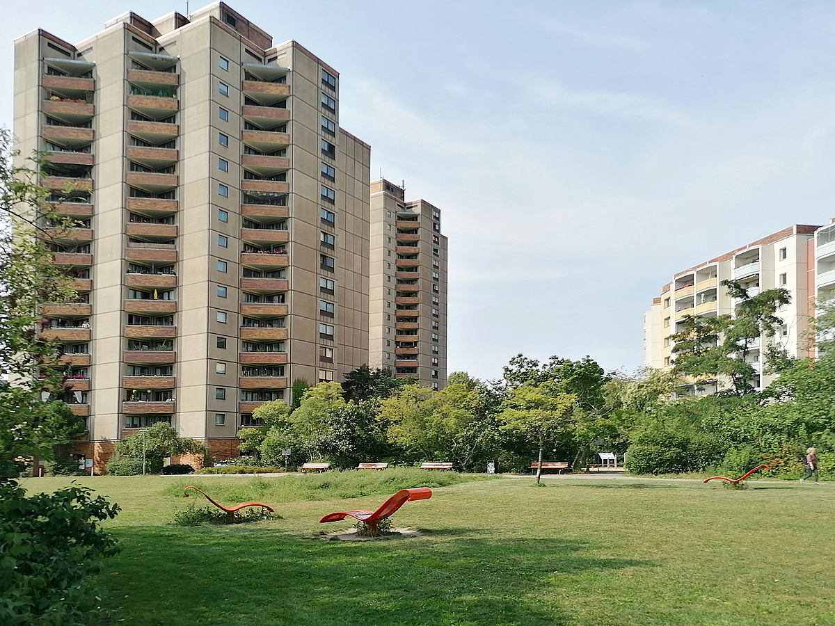 Sonnenliegen auf Wiese vor Hochhäusern