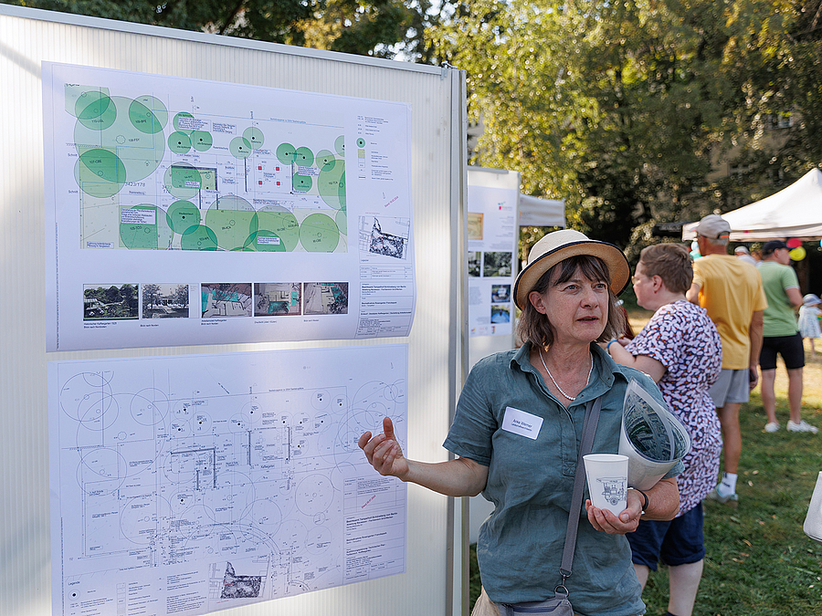 Landschaftsarchitektin Dr. Anke Werner hat für den Bezirk das Parkpflegewerk verfasst Frau mit Hut an Infotafel im Park