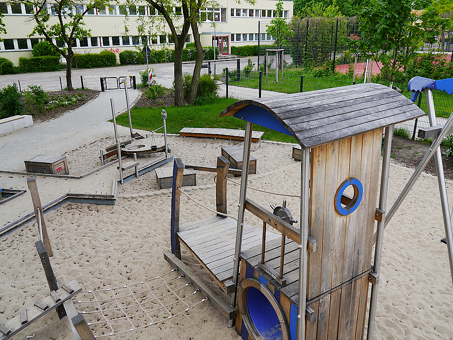 Blick von oben auf Kletterturm mit Steuerrad, Steg, Sandbaustelle