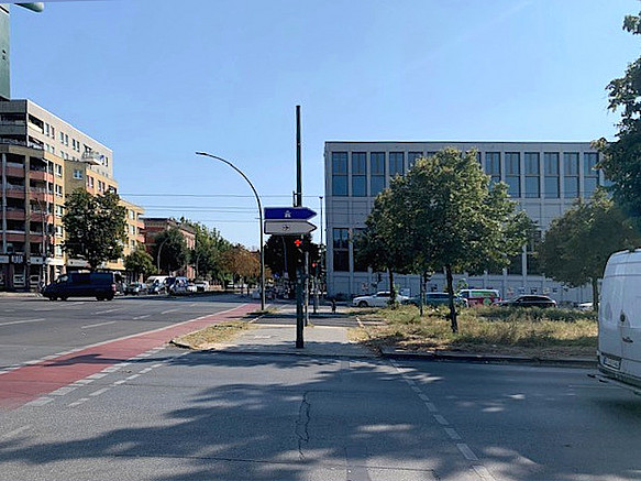 Breite Kreuzung mit grünem Mittelstreifen, modernen und Altbauten