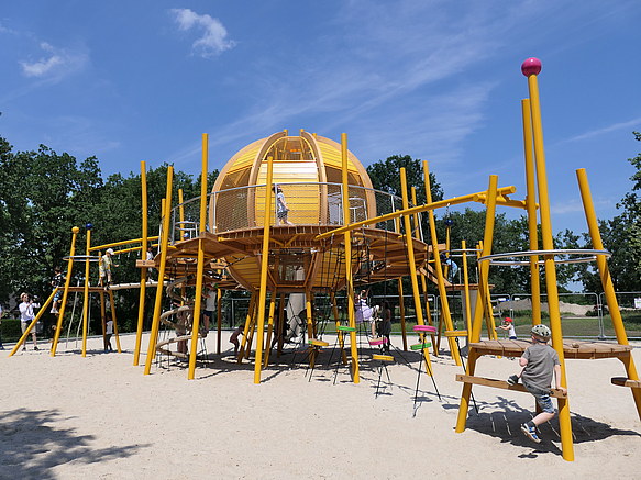 Großes Kletterspielgerät mit Kugel im Zentrum auf Sandfläche