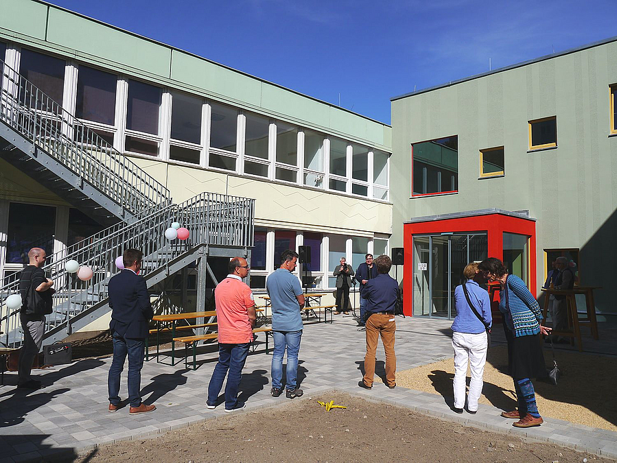 Hof in Gebäudeecke, Zuschauer Rückenansicht, gewinkelte Treppe aus dem 2. OG