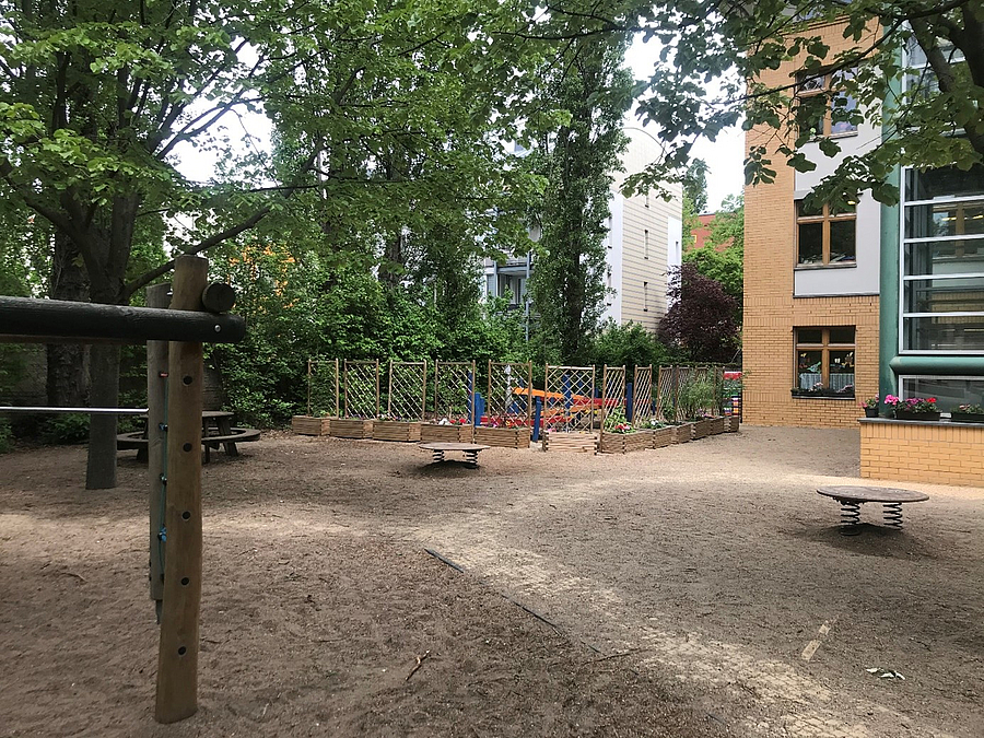 Gebäudeecke und Schulhof mit Reckstange und 2 Wackelplatten
