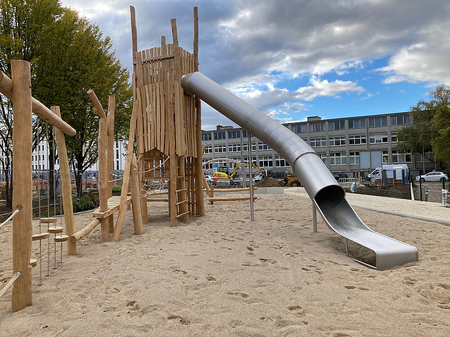 Großer Rutschenturm auf Sandspielfläche mit Balancierelementen